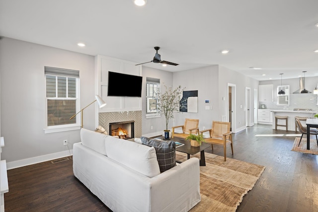 living room featuring ceiling fan, dark hardwood / wood-style flooring, and a tile fireplace