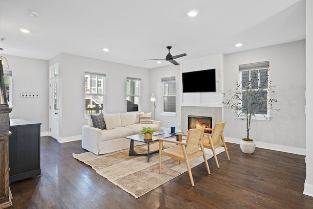 living room with a tile fireplace, dark hardwood / wood-style floors, and ceiling fan