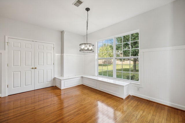 unfurnished dining area featuring a chandelier and light hardwood / wood-style flooring