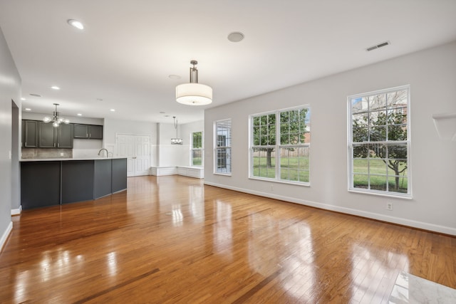 unfurnished living room with hardwood / wood-style flooring and an inviting chandelier