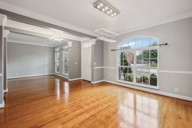 unfurnished living room featuring a notable chandelier, hardwood / wood-style flooring, and crown molding