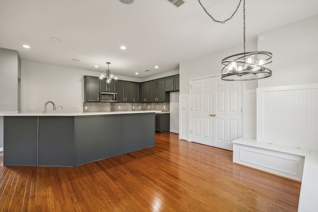 kitchen featuring gray cabinetry, decorative light fixtures, decorative backsplash, hardwood / wood-style flooring, and a chandelier