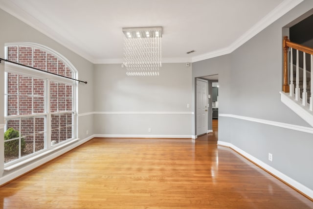 empty room featuring an inviting chandelier, wood-type flooring, and crown molding