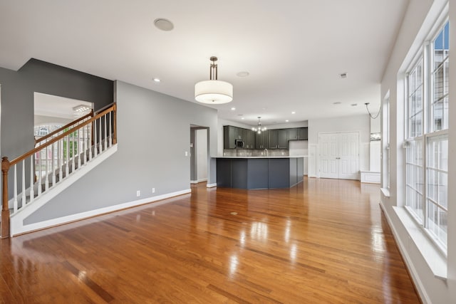 unfurnished living room featuring plenty of natural light, wood-type flooring, and an inviting chandelier