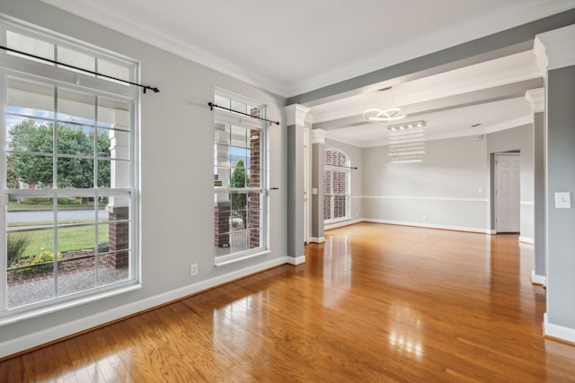 empty room with a wealth of natural light, wood-type flooring, and ornamental molding