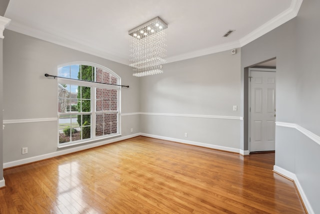 unfurnished room with hardwood / wood-style floors, a chandelier, and ornamental molding