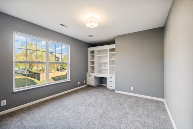 unfurnished bedroom with built in desk and carpet flooring