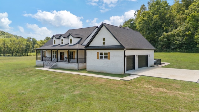 rear view of property featuring a garage, covered porch, and a yard