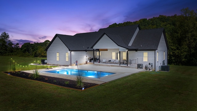 back house at dusk featuring central AC unit, a patio, and a yard