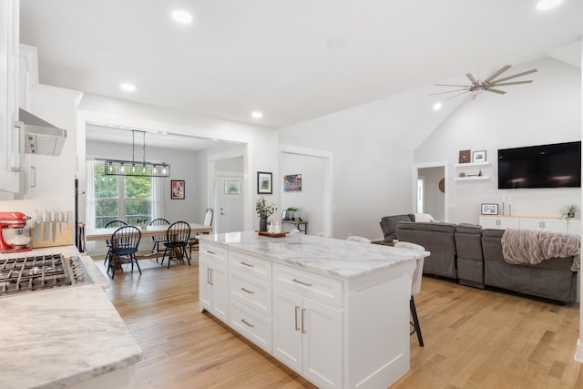 kitchen with white cabinets, light hardwood / wood-style floors, pendant lighting, and a kitchen island