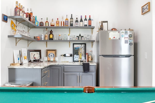 bar featuring sink and stainless steel fridge