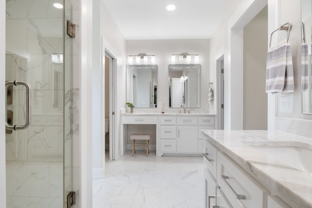 bathroom featuring a shower with door and vanity