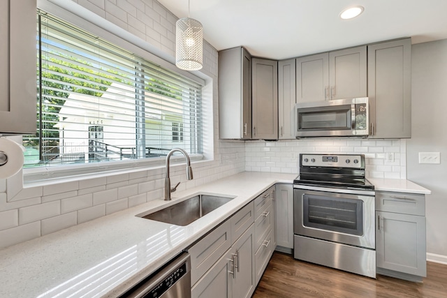 kitchen featuring tasteful backsplash, appliances with stainless steel finishes, dark wood-type flooring, gray cabinets, and a sink