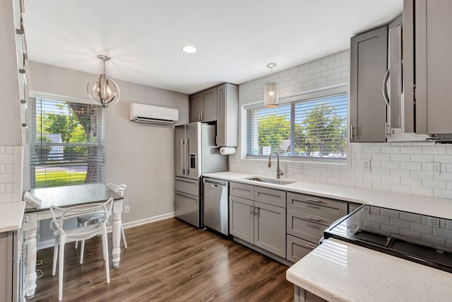 kitchen featuring appliances with stainless steel finishes, gray cabinets, a wall unit AC, and a sink