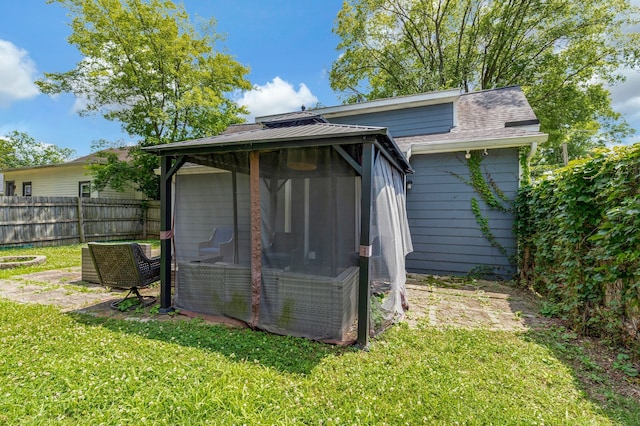 back of property featuring a gazebo, a shingled roof, a lawn, and fence