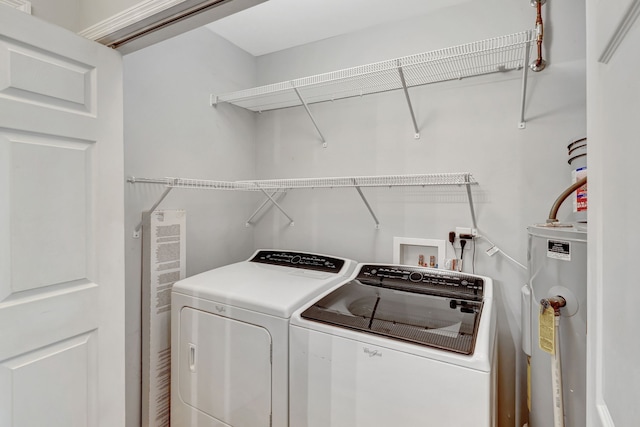 washroom featuring water heater, laundry area, and separate washer and dryer