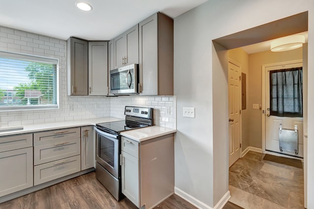 kitchen featuring appliances with stainless steel finishes, light countertops, backsplash, and gray cabinetry