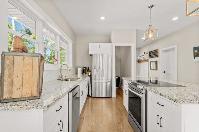 kitchen with white cabinetry, sink, light hardwood / wood-style floors, decorative light fixtures, and appliances with stainless steel finishes