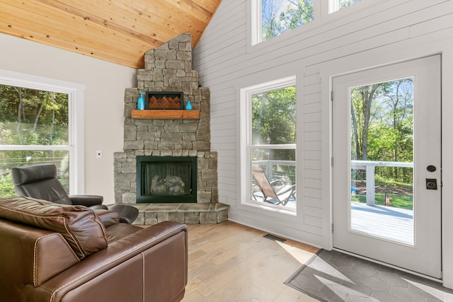 living room featuring a fireplace, light hardwood / wood-style flooring, plenty of natural light, and wooden ceiling