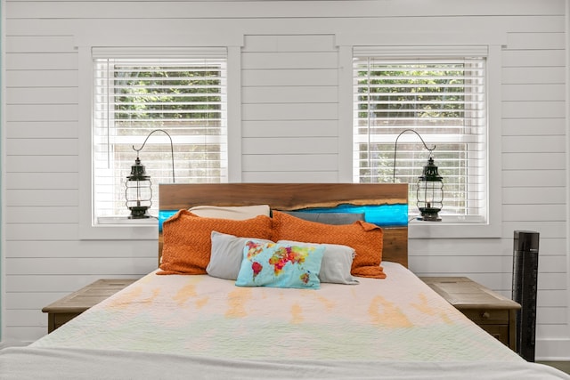 bedroom featuring wooden walls and multiple windows