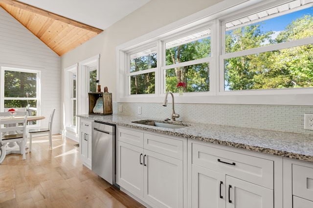 kitchen featuring light stone counters, tasteful backsplash, stainless steel dishwasher, and sink