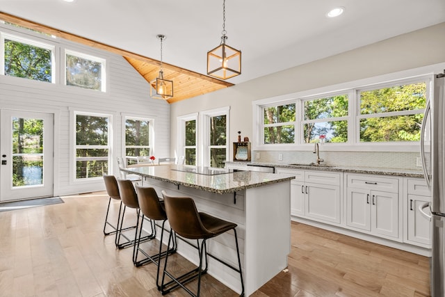 kitchen with pendant lighting, plenty of natural light, light stone countertops, and white cabinetry