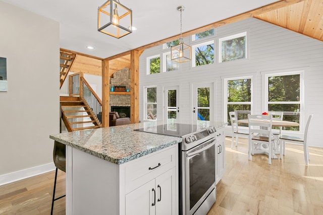 kitchen with decorative light fixtures, white cabinetry, a wealth of natural light, and stainless steel range with electric cooktop