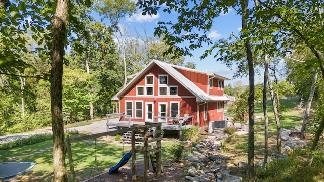 back of house with a playground and a deck