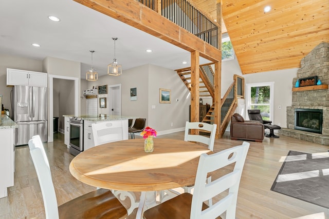 dining room featuring light hardwood / wood-style floors, a stone fireplace, and a towering ceiling