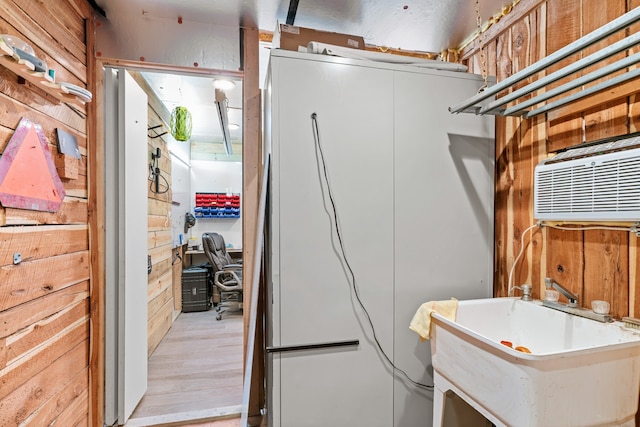 interior space with sink, light hardwood / wood-style floors, and wood walls