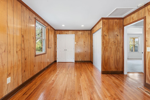 unfurnished bedroom with wood walls, light hardwood / wood-style flooring, and ornamental molding