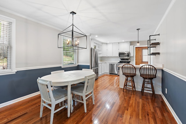 dining room with ornamental molding, dark wood-type flooring, and a chandelier