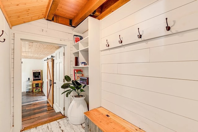 mudroom with lofted ceiling with beams, a barn door, wooden walls, hardwood / wood-style floors, and wooden ceiling