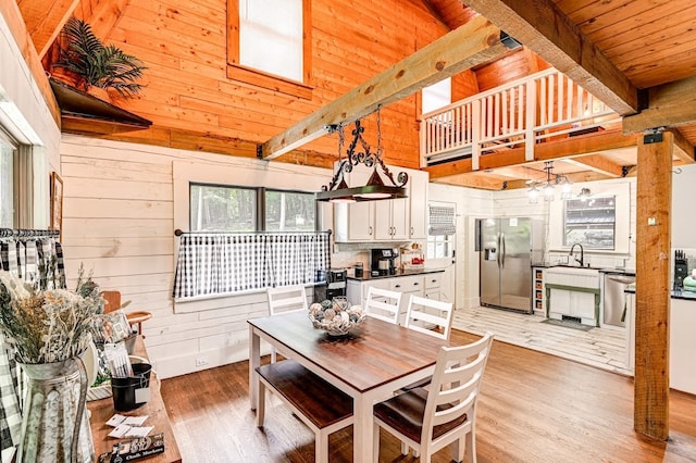 dining space featuring wood ceiling, wood-type flooring, wooden walls, and beam ceiling