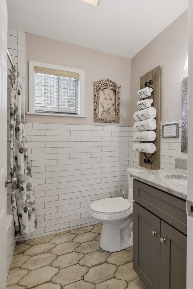 full bathroom with tile walls, vanity, toilet, and shower / bathtub combination with curtain