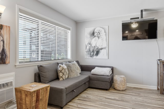 living room with a wall mounted air conditioner, light hardwood / wood-style flooring, and ornamental molding