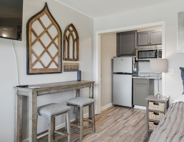 kitchen with gray cabinets, ornamental molding, white fridge, and light hardwood / wood-style flooring