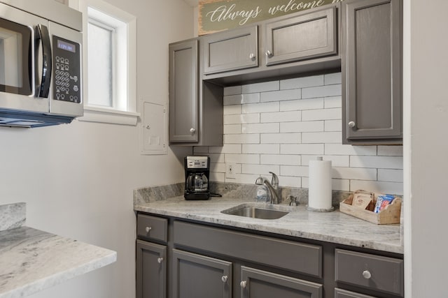 kitchen with gray cabinets, light stone countertops, and sink