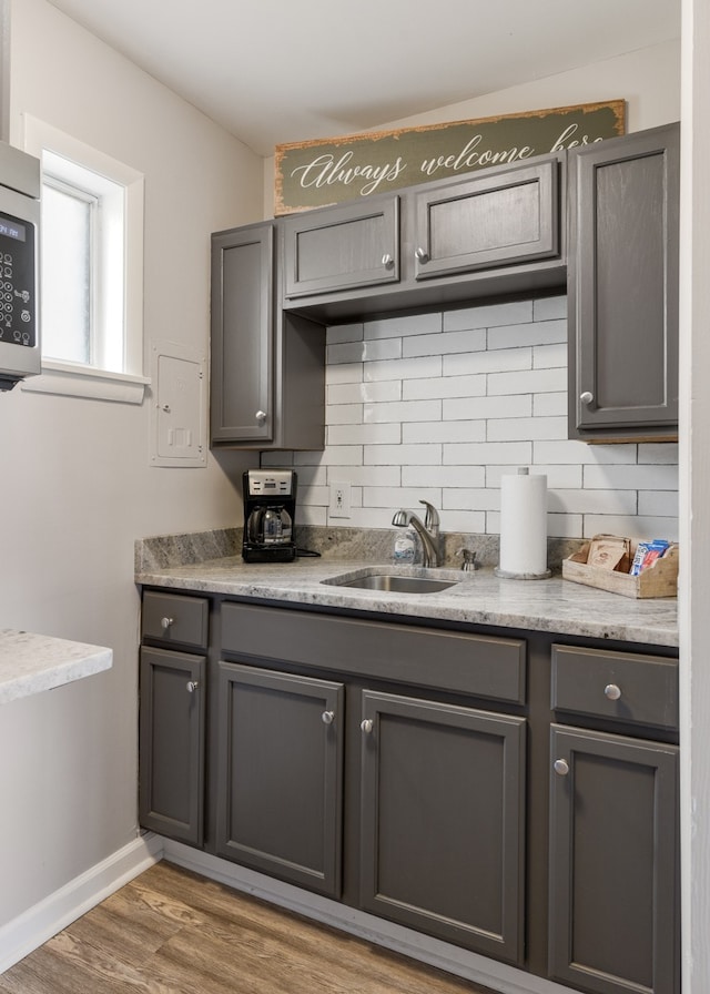 kitchen featuring tasteful backsplash, sink, light stone counters, and dark hardwood / wood-style floors