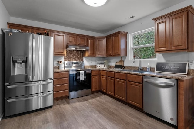 kitchen with stainless steel appliances, sink, tasteful backsplash, and hardwood / wood-style floors