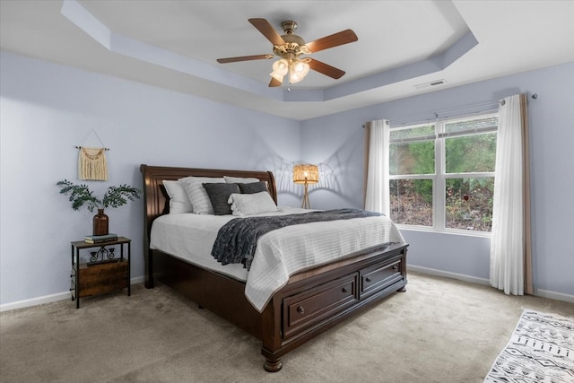 bedroom featuring light colored carpet, ceiling fan, and a raised ceiling