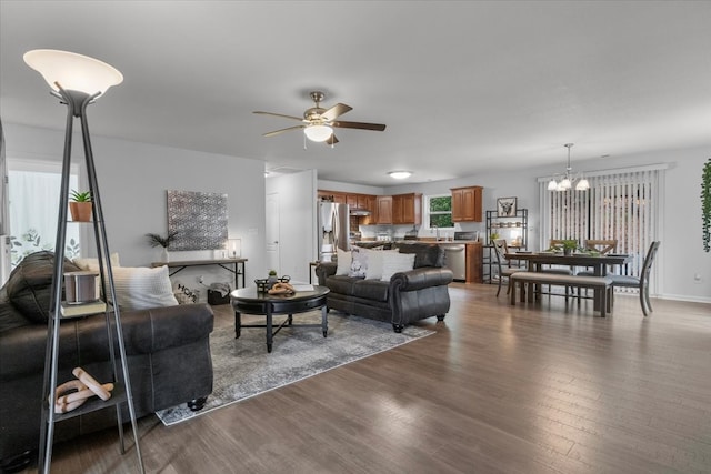 living room with dark wood-type flooring and ceiling fan with notable chandelier