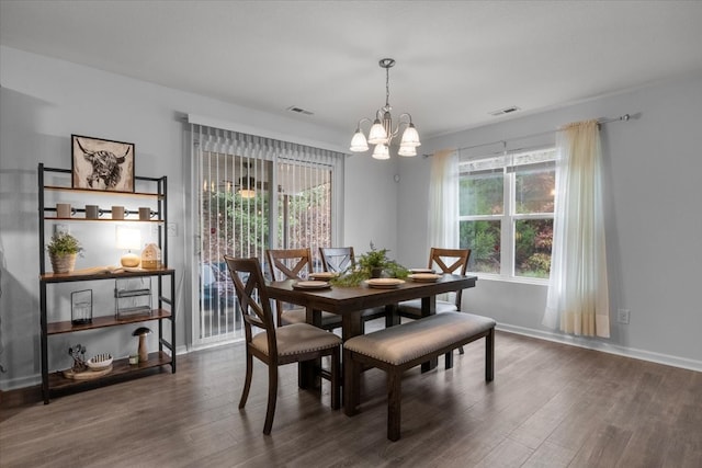 dining space with dark hardwood / wood-style flooring and an inviting chandelier