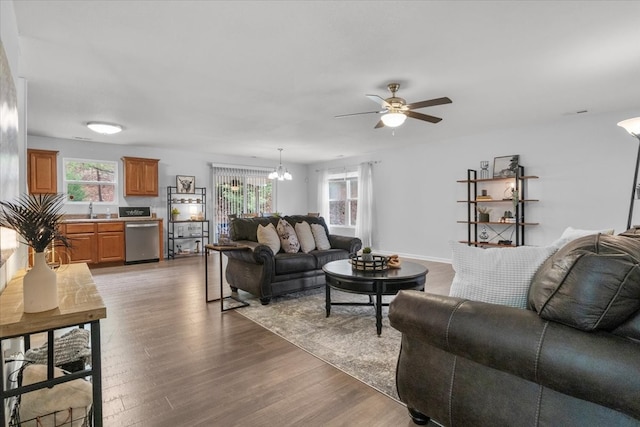 living room featuring dark wood-type flooring, sink, and ceiling fan with notable chandelier