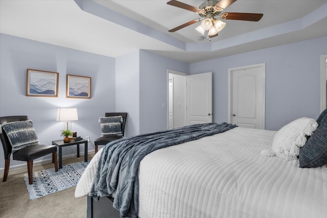 carpeted bedroom featuring ceiling fan and a raised ceiling