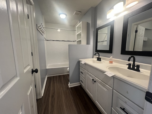 full bathroom with toilet,  shower combination, hardwood / wood-style floors, a textured ceiling, and vanity