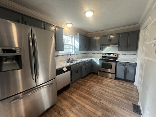 kitchen with stainless steel appliances, sink, crown molding, gray cabinetry, and dark hardwood / wood-style flooring