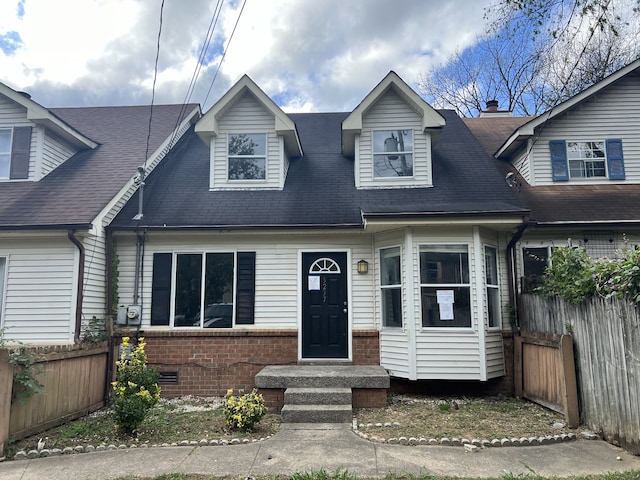 view of front facade featuring crawl space, brick siding, and fence