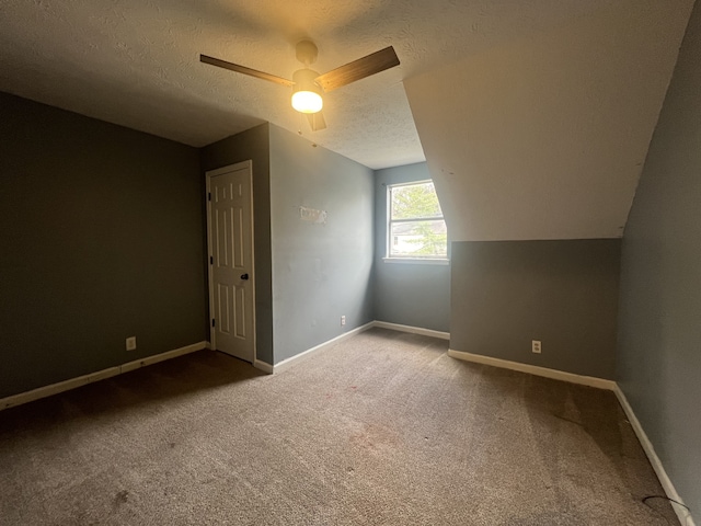 additional living space with carpet, a textured ceiling, ceiling fan, and vaulted ceiling