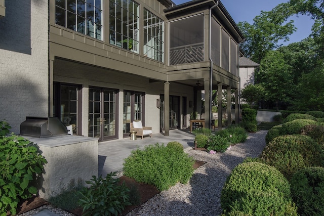 rear view of property with a patio, a sunroom, french doors, and an outdoor kitchen